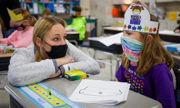 Teacher talks to student at desk